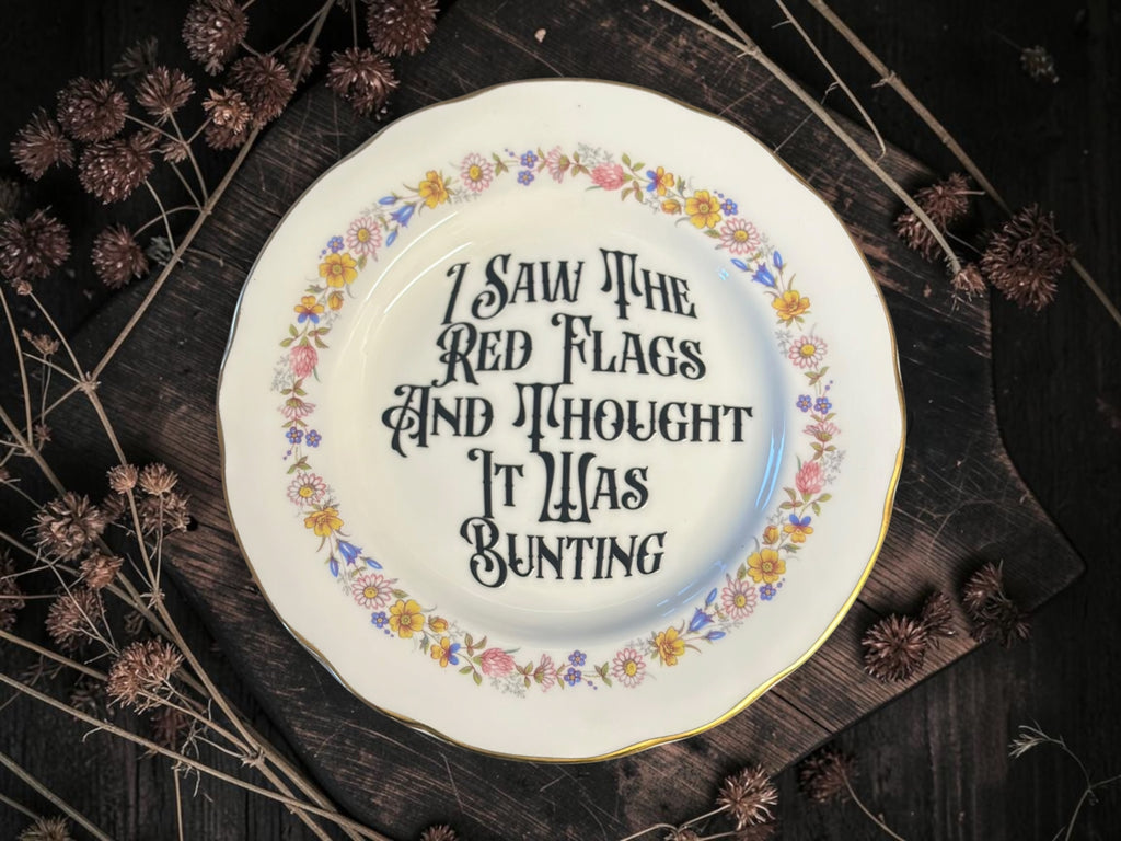 Vintage decorative plate reading I Saw the Red Flags and Thought It Was Bunting